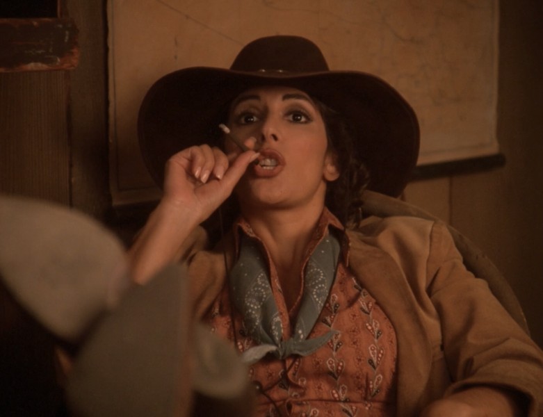 Deanna Troi from Star Trek TNG in a western holodeck mission, with her feet up, smoking a cigar